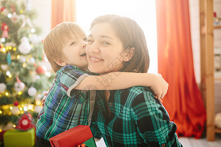 快乐的家庭妈妈和儿子在圣诞节冬天阳光明媚的早晨在装饰圣诞树和礼物的圣诞庆祝室里 女士 孩子图片