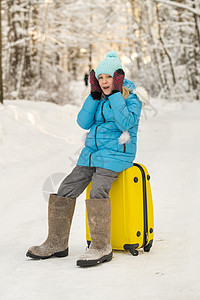 冬天 一个穿有感觉靴子的女孩 在寒冷的雪天坐在手提箱上 成人 森林图片