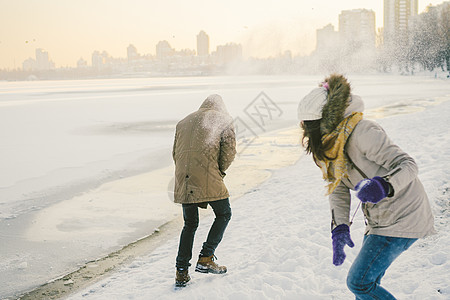 年轻的白种人相爱的异性恋夫妇在冬天在结冰的湖边约会 活跃假期情人节 打雪球玩欢乐 男人 手套图片