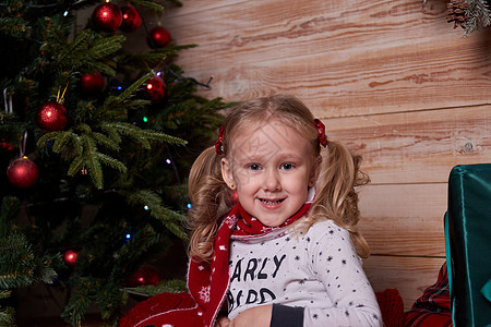 穿着睡衣的女孩的肖像 坐在圣诞树下面的床上 带着礼物在礼品盒里 父亲 房间图片