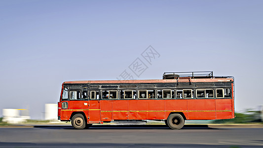 在马哈拉施特拉邦的无空调红色城市间公交车在街上超速 背景模糊图片