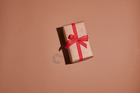 现今或礼品盒包装在手工艺纸中 并用心放在壁画背景上 玫瑰 丝带图片