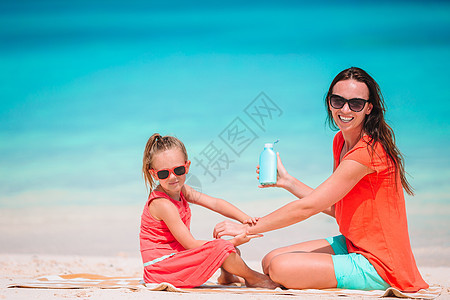年轻母亲在沙滩上给女儿鼻子涂防晒霜 保护太阳 洗剂 孩子图片