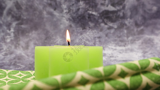 在美丽的灰色大理石背景下 桌上放着一根绿色点燃的蜡烛 上面放着绿色亚麻餐巾 您的文本的地方 圣诞节装饰 芳香疗法 桌子图片