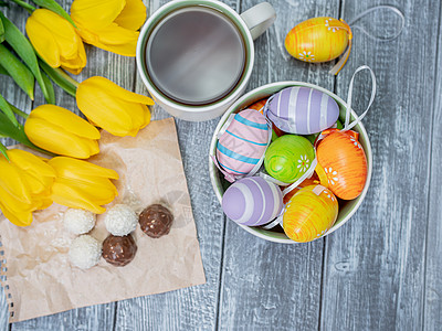 复活节彩蛋和郁金香在桌子上 从上面看 在一个白色杯子和巧克力的茶图片