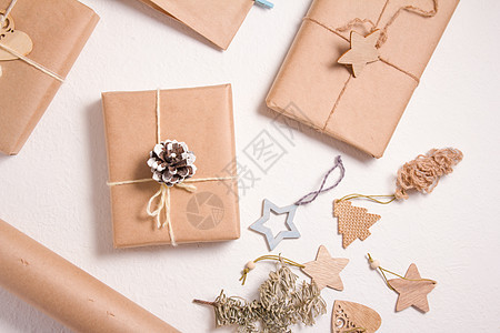 圣诞节或新年的生态友好礼品箱包装 木制圣诞玩具 用圆皮纸包着的盒子和白底面的木星 并配有树枝 乡村 装饰品图片
