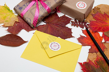 感恩节背景 带题词的黄色信封谢谢你 带漂亮丝带的礼物 白桌上的枫叶秋叶 复印空间 平躺 顶视图 感恩节 假期图片