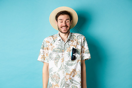 享受暑假 穿着草帽和哈瓦伊衬衫 在蓝背景上站得愉快的游客快乐 脸 成功图片