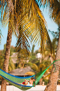 在热带度假的吊床上带笔记本电脑的青年男子 棕榈树 愉快图片