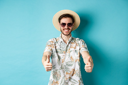 享受暑假 站在白色背景的白底脸下 在太阳镜和草帽中快乐的观光者举起拇指微笑 时尚 胡须图片