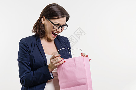 惊讶的成年妇女寻找购物袋 白背景和白色背景图片