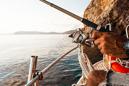 在公海上游帆船上捕鱼时 紧紧握着渔棍的雄手 水 夏天图片