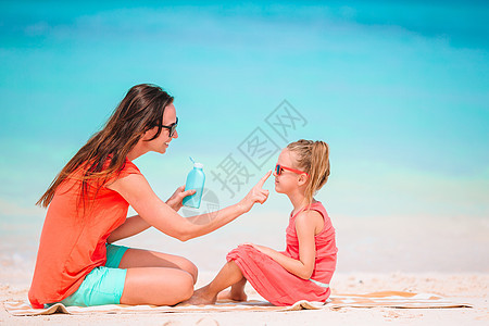 年轻母亲在沙滩上给女儿鼻子涂防晒霜 保护太阳 皮肤图片