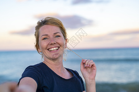 跟我来 — 快乐的年轻女人拉着男人的手 — 手牵手走在夕阳的海边 — 无忧无虑的现代生活理念 中年 喜悦图片