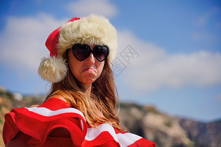 穿着红色泳衣和圣诞老人帽子的年轻有吸引力的黑发女人 在海滩上 圣诞节假期和旅行问题的概念 笑声 娱乐 比基尼图片