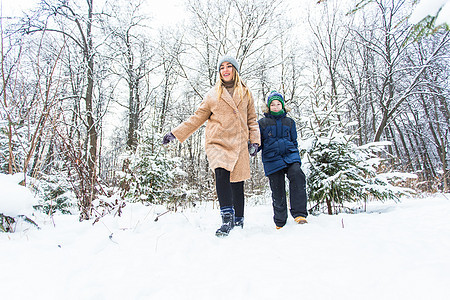 父母 欢乐与季节概念——快乐的母亲和儿子在冬季森林中玩得开心 玩雪游戏 寒冷的 自然图片