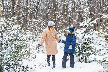 欢乐与季节概念-快乐母亲和儿子在冬季森林中玩得开心 玩雪游戏 童年 男朋友图片