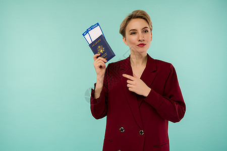 一个穿着红色西装的现代时尚微笑的女人 带着机票和护照在她手上图片