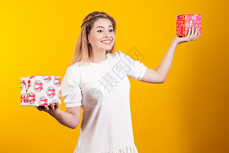 一个身着白裙子的快乐女孩的肖像 她拿着两个小礼物盒 看似神魂颠倒图片