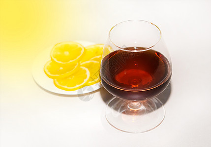 杯中一杯白兰地 旁边是盘子上切柠檬边 酒精和零食概念图片