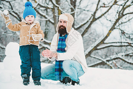 冬天 父子俩在户外玩耍 快乐的爸爸和孩子在冬天玩耍 圣诞节的时候 快乐的孩子在白色的冬天背景下玩雪球 幸福有爱的家庭图片