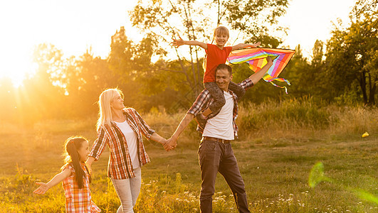 母亲和女儿的幸福家庭父亲在日落时发出关于自然的风筝 自由 女孩图片