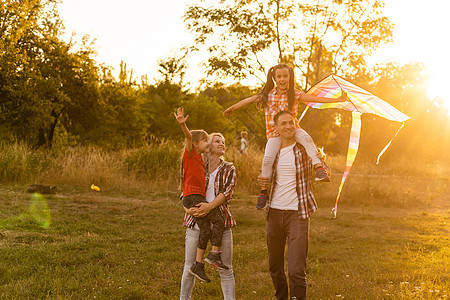 母亲和女儿的幸福家庭父亲在日落时发出关于自然的风筝 孩子 童年图片