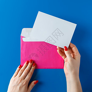 粉红信封 有一张空白卡 在蓝色背景的手中 卡片 经典蓝图片