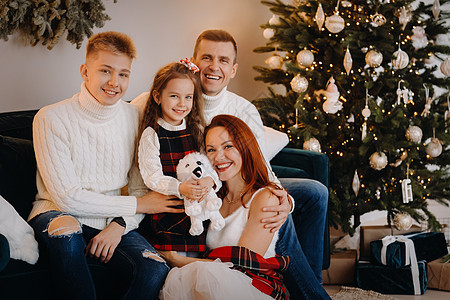 一个幸福的家庭坐在庆祝节日的圣诞树附近的沙发上的近似肖像 冬天 母亲图片