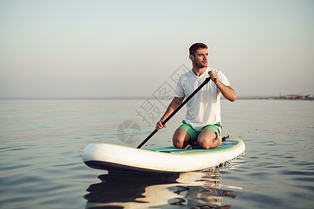 身穿T恤衫和短裤的年轻人在SUP板上漂浮 冲浪 娱乐图片