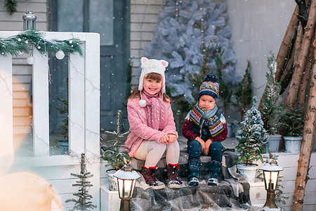 快乐的小孩们坐在圣诞礼堂门廊上 户外装饰房子 下雪 庆典图片
