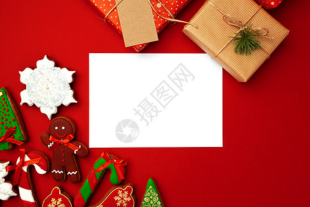 带圣诞礼物和红背景姜面包饼干的空白纸纸薄纸页 问候卡 食物图片
