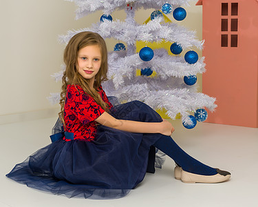 可爱女孩在装饰的白色圣诞树前游荡 坐着 快乐的图片