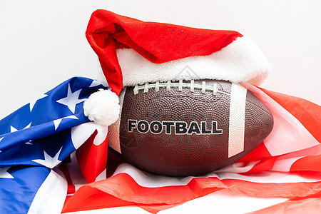 橄榄球或美式足球的纪念球 戴着绿色背景的红色圣诞老人帽子 准备设计体育主题的门票 海报 明信片或名片 快乐的 成功图片