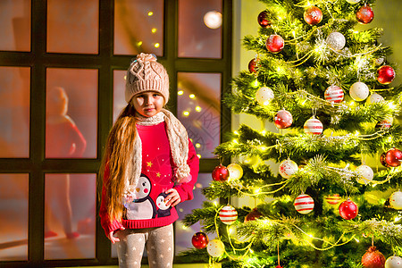 小女孩装饰圣诞树 新年概念 家庭节日 灯图片
