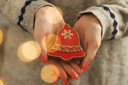 一个穿着喜庆毛衣的女人手 拿着灯光模糊的姜饼饼干 甜的 冬天图片