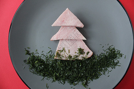 可食用的圣诞树和香肠在灰色盘子上 红色背景上有圣诞树的树枝 文本复制空间的位置 有趣的儿童食品 圣诞老人 装饰风格图片