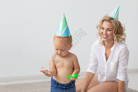 年轻笑笑的妈妈和可爱的小女儿穿着生日帽子 一起在家地毯上共度时间的家庭节假日和价值 迷人的 纯真图片