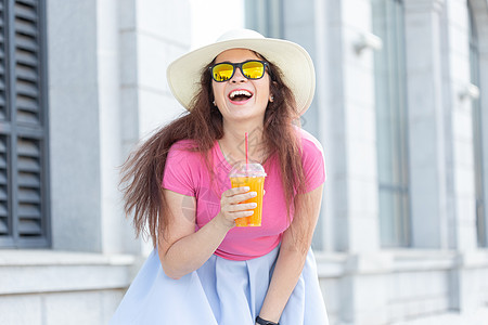 在一个温暖的夏日里 一位戴着帽子和眼镜的美丽时尚年轻女子的特写肖像在城市里走来走去 快乐积极的人的概念 魅力 青年图片