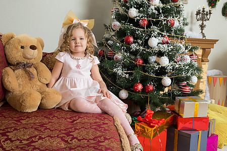 圣诞女孩插画女孩和泰迪熊坐在沙发上的圣诞树旁边 孩子们 庆典背景