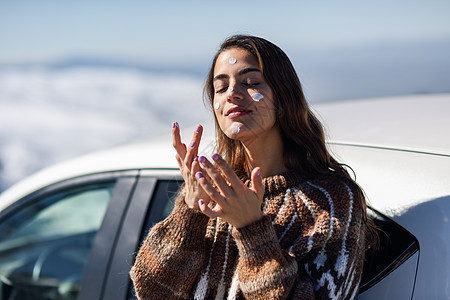 年轻女子在雪地上用防晒霜遮住她的脸 洗剂 奶油图片