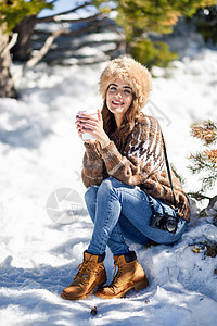 年轻女子在冬天享受雪山的寒冬 时尚 毛衣 茶图片