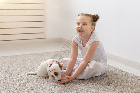 人 儿童和宠物的概念 — 小女孩和可爱的小狗坐在地板上玩耍 假期 犬类图片