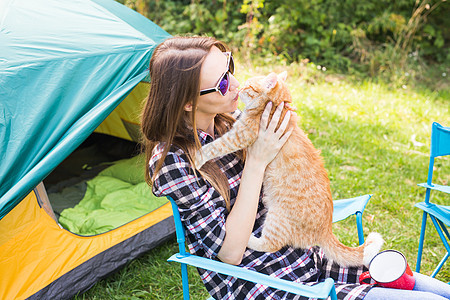 人民 旅游和自然概念   太阳镜中的妇女坐在帐篷旁边的猫 营地 旅行图片