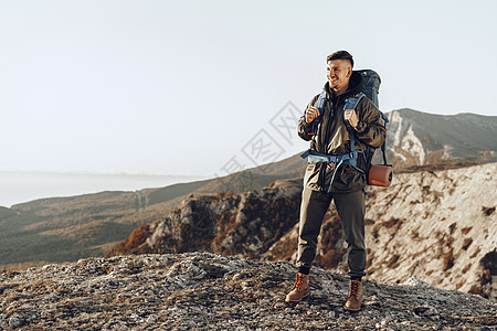 年轻的天主教男子旅行者 在山上徒步旅行 背着大背包在山上远足 攀登 天空图片