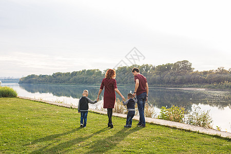 妈妈儿子为人父母与自然概念 — 母亲和父亲的家庭 有两个男孩双胞胎孩子在夏天在河边的公园里 在阳光明媚的日子 周末 孩子们背景