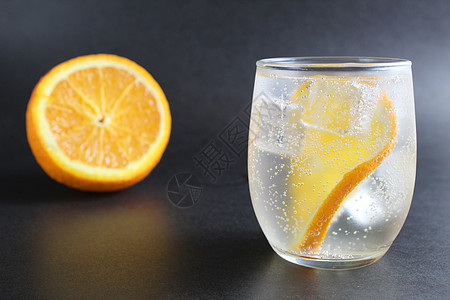 黑色背景中一杯柠檬水加橙子和冰块 旁边是冰块和橙子 黑色背景下的夏日饮品 嘶嘶声 寒冷的图片