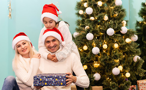 一个孩子带着圣诞节礼物 微笑着在相机上笑着的喜悦 问候语 在家里背景图片