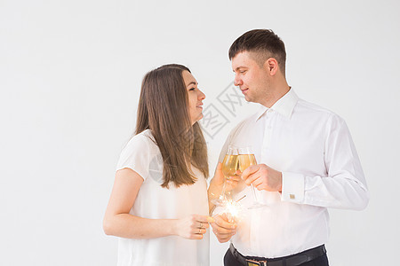新年 假期 约会和情人节概念 — 恩爱的情侣在白色背景下拿着烟火和香槟 庆典图片