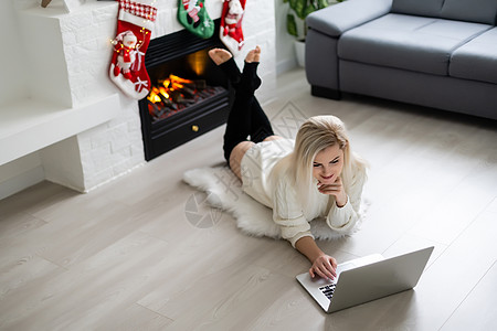 全世界一触即发的金发美女 在笔记本电脑上工作 并微笑着圣诞背景 笑声 树 公寓图片